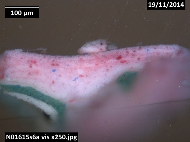 Colour photograph. A microscopic cross section of paint shows a layer of white paint covered first by green and then pink. Text in the upper corners read, “100 µm” and “19/11/2014”. A label in the lower left reads, “N01615s6a vis x 250.jpg”.