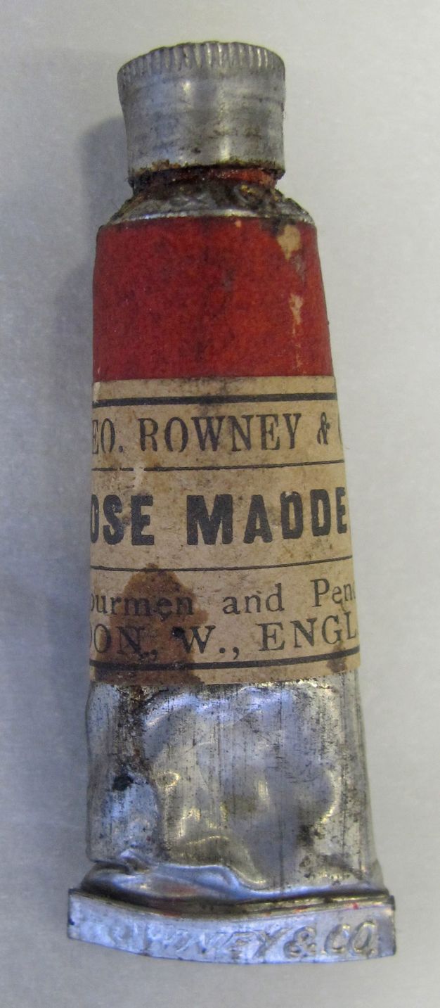 Silver paint tube has a label with red at the top over the text, “Rowney &” above the partial name of the colour, which his rose madder.