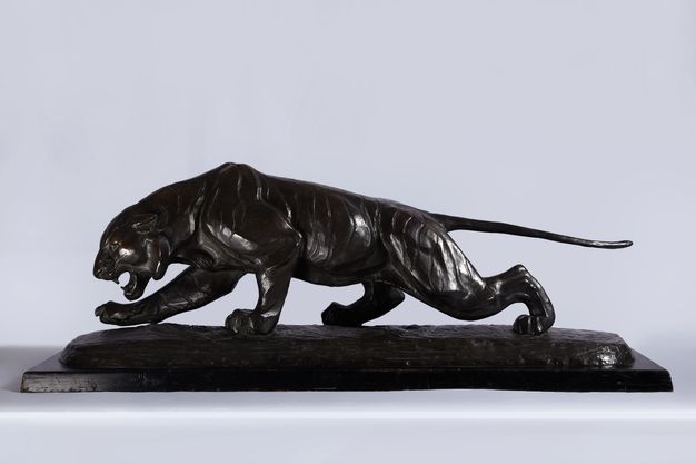 Sculpture. A tiger prowls, its body low to the ground and mouth open, in this bronze statuette. The tail extends straight back, and the head is lowered. One front paw is lifted. The animal stalks on a cast bronze base.
