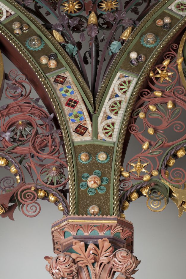 Choir screen. Detail view of where two arches spring from a shared capital. Metalwork, like paper quilling, painted gold, glass, stone, and enamelled patterns create a jewelled effect.