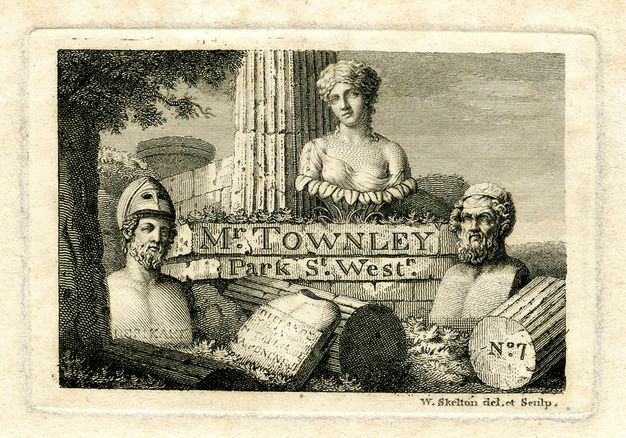 Print. Black lines on cream paper show three classical busts arranged at the base of a ruined column overgrown with vegetaion. Fragments of the column, and a tablet with an illegible inscription, surround them. On the base of the column, text reads “Mr. Townley Park St. West”.