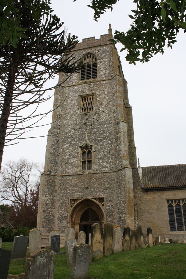 Architecture. A four-storey, wide stone tower rises over a porch projecting from the side of a church. Each level is slightly narrower than the last.
