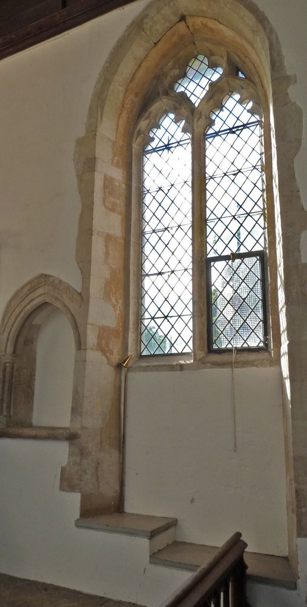 Architecture. The sill below a window with clear glass and diamond-shaped leading drops far below the bottom edge of the panes, near the floor of the church. It steps down to create two deep ledges.
