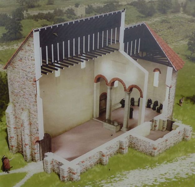 Reconstruction. The side of a stone church has been cut away to show a short nave separated from a rounded space by columns holding up arches over the altar. The back area has a bench around its half-moon perimeter. Tiny people in black monk's robes sit along its length.