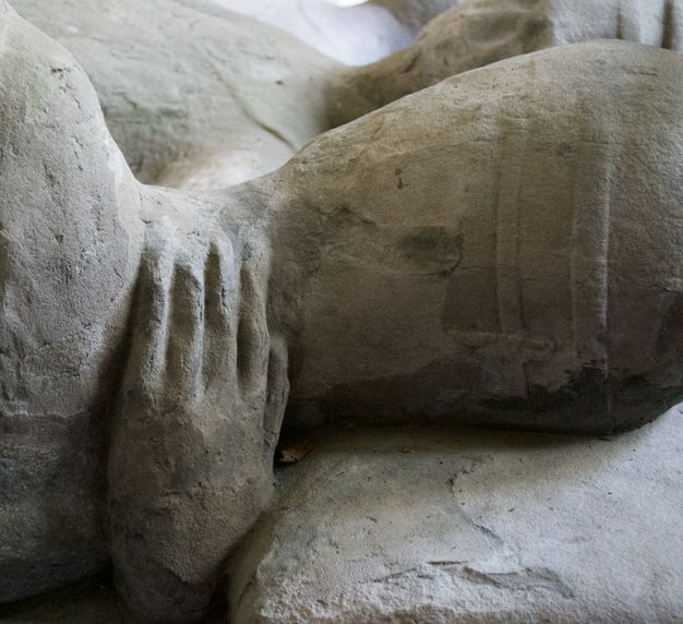 Sculpture. Detail view of a hand embracing the back of a second person’s neck in this carved memorial.
