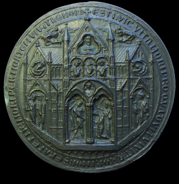 Seal. The reverse of a round seal is cast in dark green material. The double arched door of a church portal frames two people. The head of a man is in a trefoil above, and more people are under arches and in roundels across the church. Angels are to either side of the tower over the central door. Latin text lines the perimeter.
