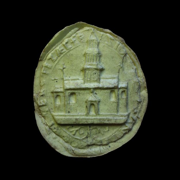 Seal. Cast in light green material, the circular seal shows a church with a tall tower over the central door. Text around the perimeter is difficult to make out.