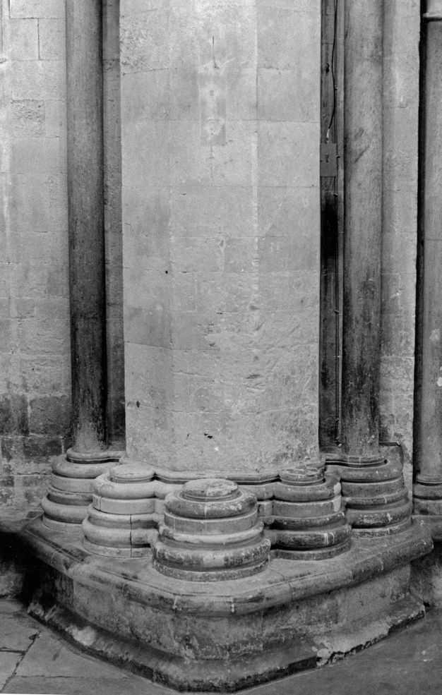 Architecture. Black and white photograph of the foot of a stone pier lined with stepped bases, awaiting disengaged shafts that were never put in place.
