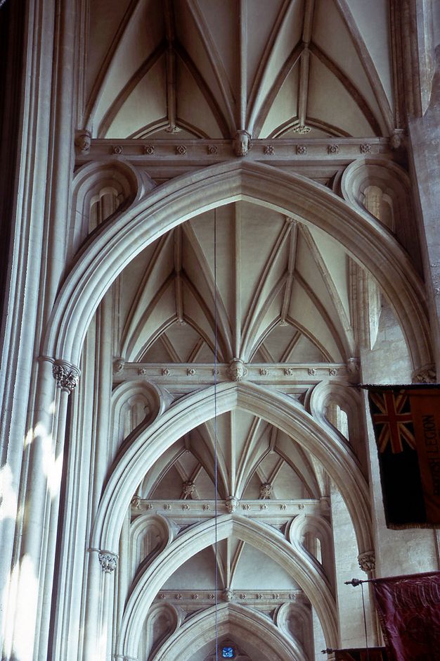 Architecture. Pointed stone arches support a second storey of miniature ribbed vaults, creating triangular spaces like camping tents.