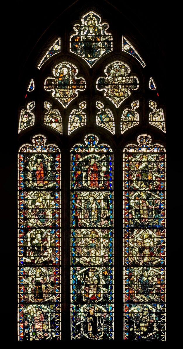 Stained glass window. Three columns of stained glass windows are set within an encompassing arch. The details of the people and objects shown in the glass are difficult to make out in this image.