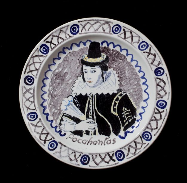 Plate. A woman wearing a black dress, a stiff white collar, and a tall black hat is shown from the waist up. She holds a feather fan in one hand. She is painted mostly in shades of blue, grey, and black, with a few touches of pale yellow. Her name is painted below, \“Pocahontas\”.
