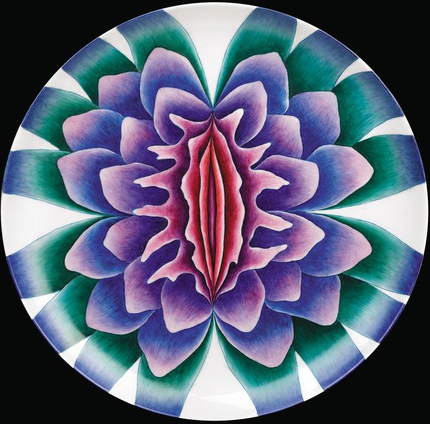 Plate. A flower is painted in jewel-like tones of pink, blue, purple and green. The central petals are vertical, narrow and pink and they become more rounded as they move out.