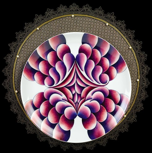 Plate. A plate painted with deep red and pink lobe-like forms extending from a clustered centre out in a wide X sits on a gold, lace-edged cloth.