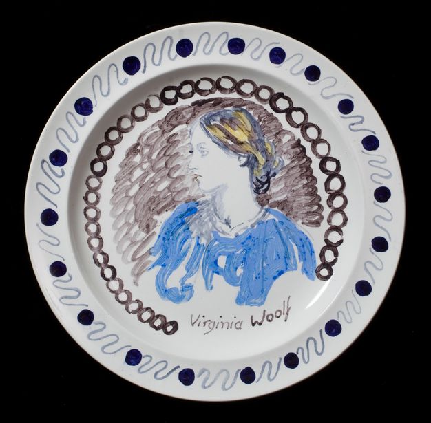 Plate. A sketchily painted woman looks off to our left in profile against a brown background. Her hair is tied up at the base of her neck and she wears a light blue dress. Her name is painted below, \“Virginia Woolf\”.