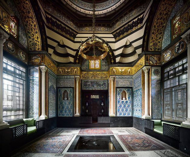 Architecture. Every surface of this room is covered in dense pattern, including the windows. A dome above rises from an octagonal drum, all overlaid with gold and black designs. Broad arches span windows screened with finely pierced shades. Mosaic floors and walls are in tones of blue, red, and gold.