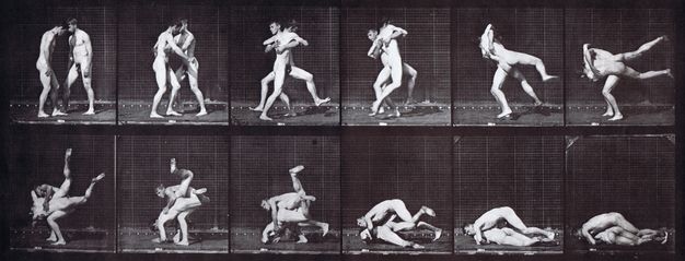 Black and white photographs. Two nude, pale-skinned men wrestle. Two rows of six frames each show different instants in their action in consecutive order across all twelve shots.