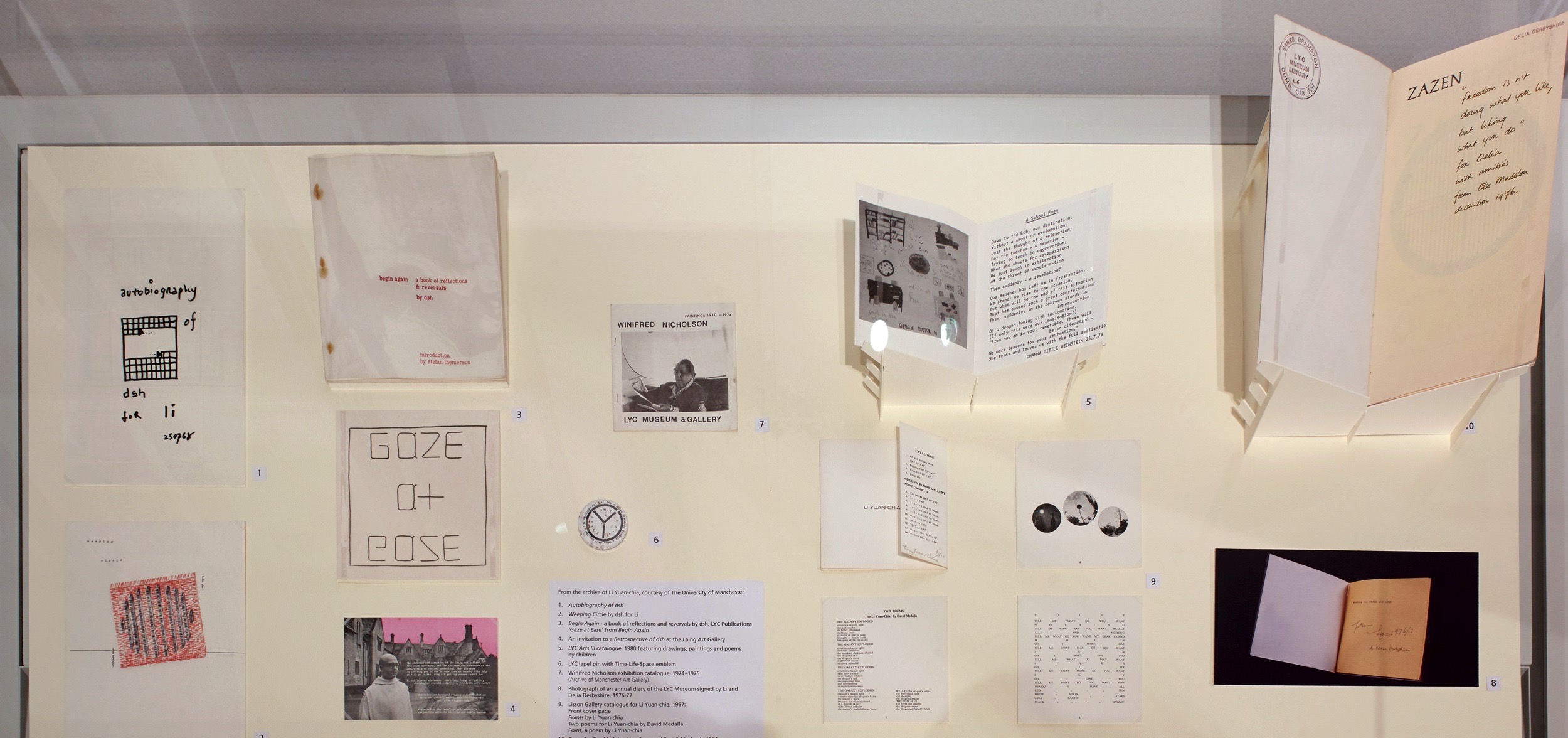 Installation. Fourteen works on paper, images, or books are displayed in a case.