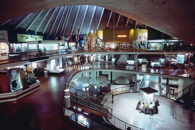 Installation. The topmost of three levels around an open space is lined with colourful exhibits.