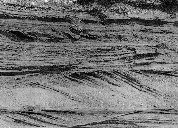 Black and white photograph. Horizontal bands of earth are independently striated in horizonal or diagonal layers.