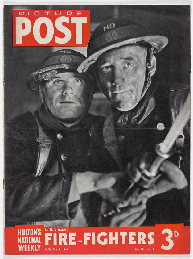 Magazine cover. A black and white photograph of two men, wearing uniforms and their pale skin dirtied, aiming a fire hose out of frame to our right, as they look up. Their eyebrows are knit and their lips set. The magazine’s name is in white text in a red box at the top left. In a red banner below, white text reads “Houlton’s National Weekly In this issue: Fire-Fighters February 1, 1941 Vol. 10 No. 5 3D”.