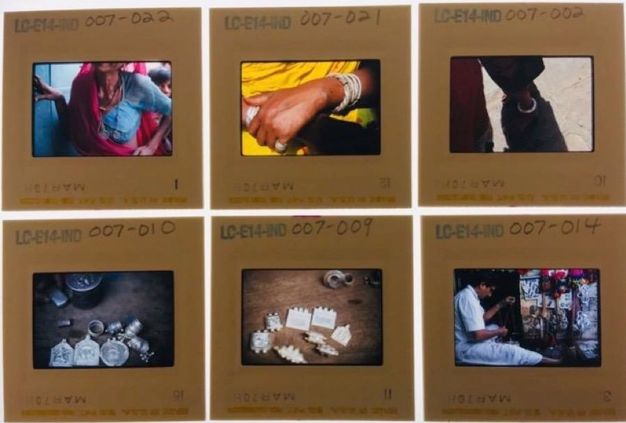 Slides. Four colour slides show close ups of an ear with rings hanging over the upper helix, silver cuff bracelets on dark-skinned arms, the lower legs and shoes of a person standing next to a bicycle, and a red turban catching light in an otherwise shadowy picture.