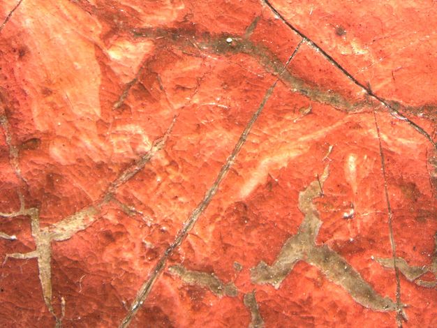 Painting. Detail view of cracks in red paint showing a grey layer beneath.