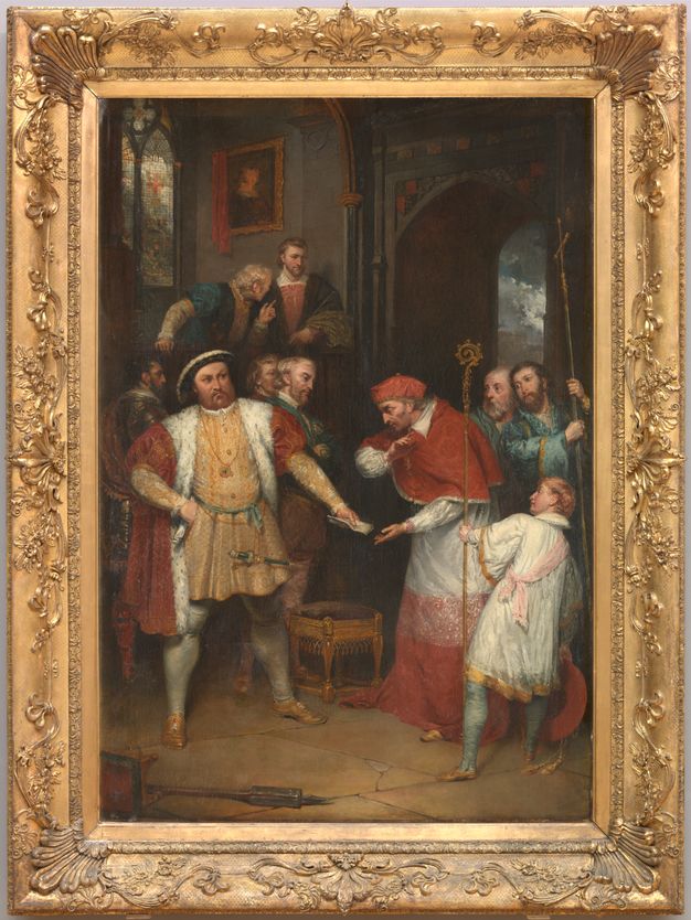 Painting. A man, Henry VIII, stands with feet widely planted, one hand on his hip as he hands a piece of paper to Thomas Wolsey, who wears red cardinal’s robes. A gold frame is decorated with vines and flowers.