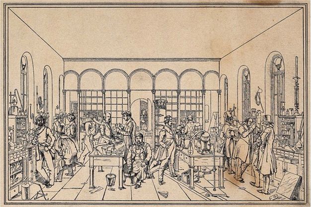 Print. Shown in black lines on light brown paper, men stand or sit at two long tables piled with equipment. Shelves also line the walls, and a few bits of paper and other detritus are scattered on the floor.